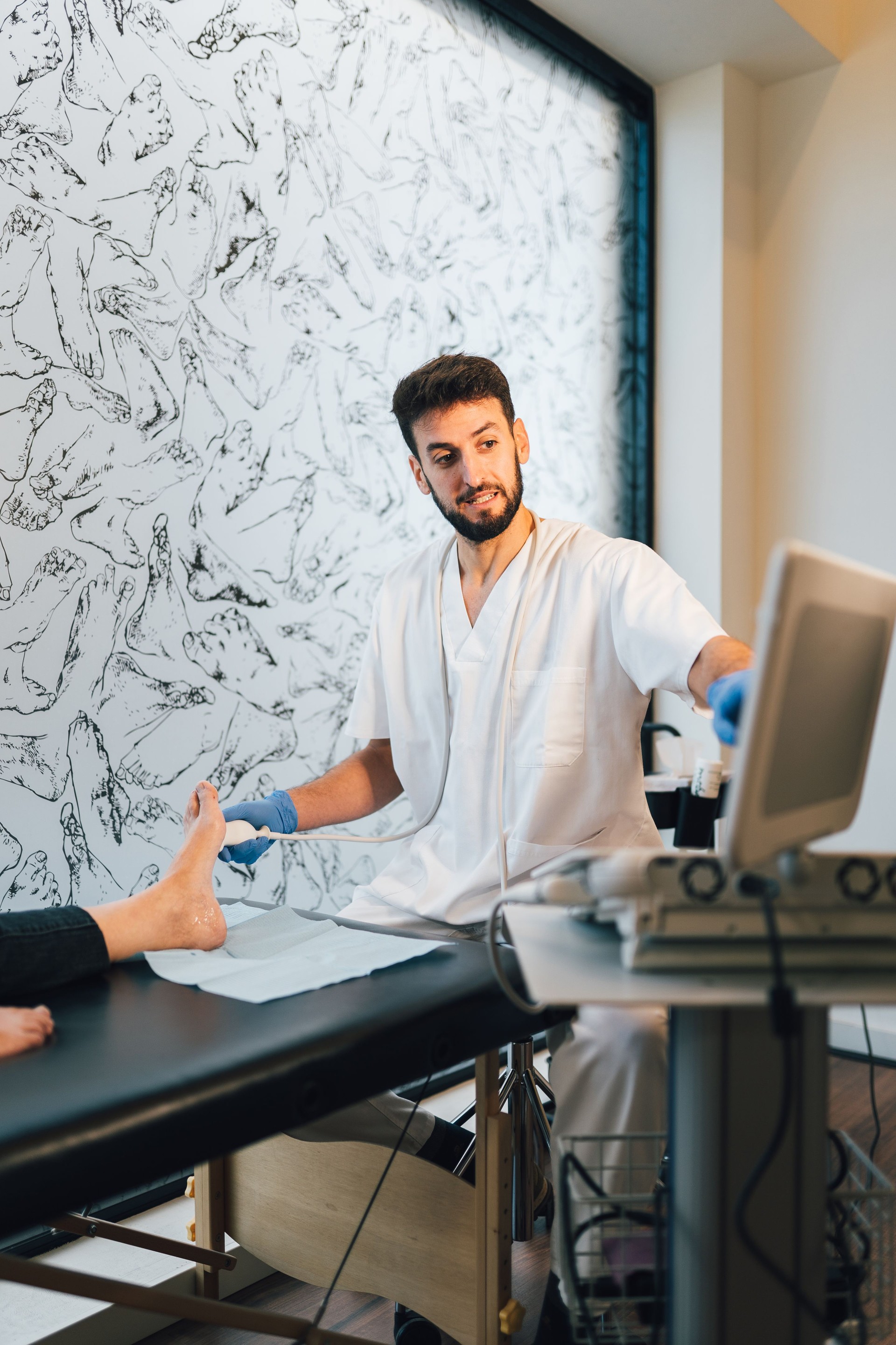 Podiatrist doing an ultrasound test to patient's foot.